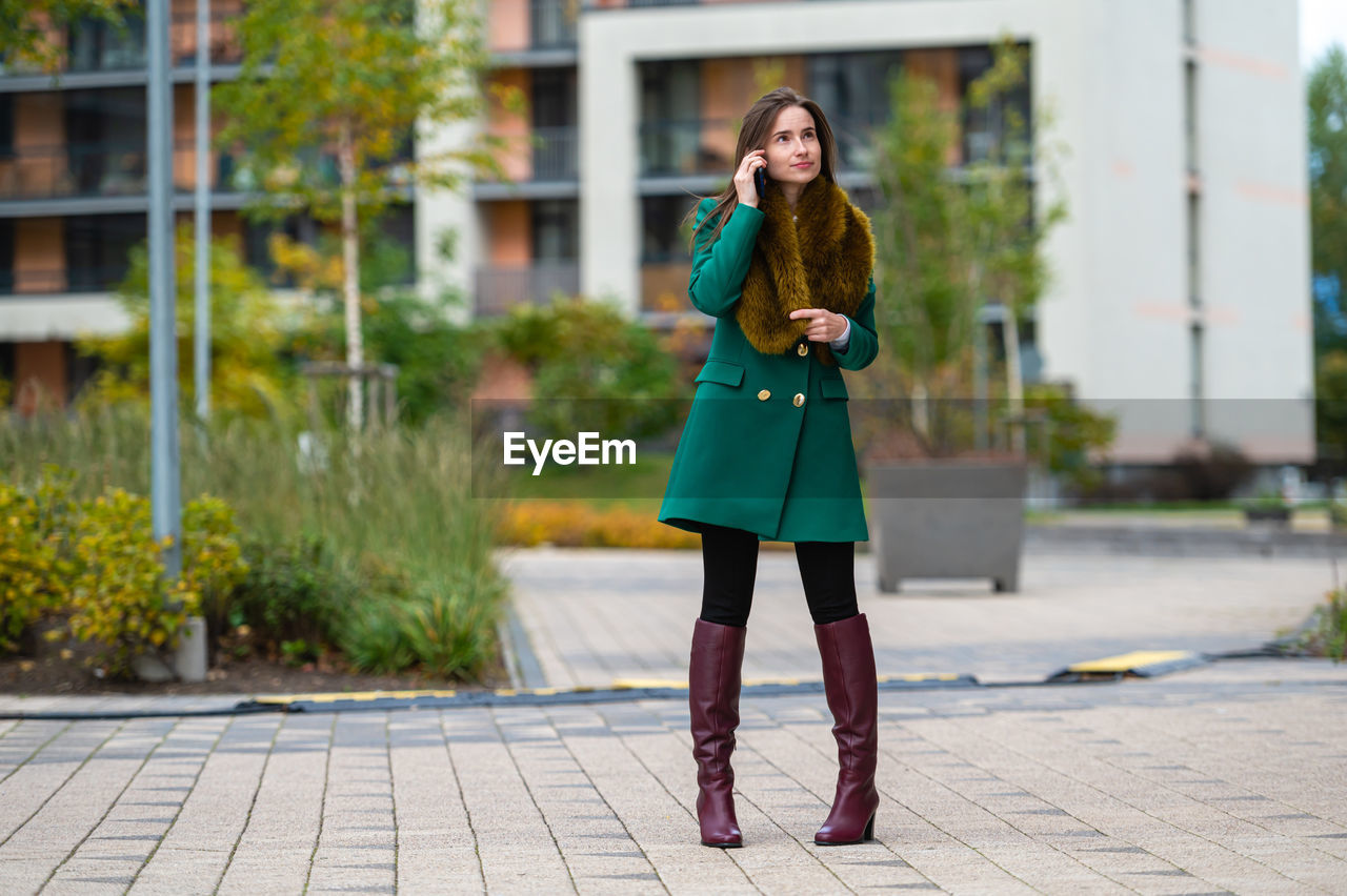 A business woman walking down the street in a financial district talking on the phone, full lenght