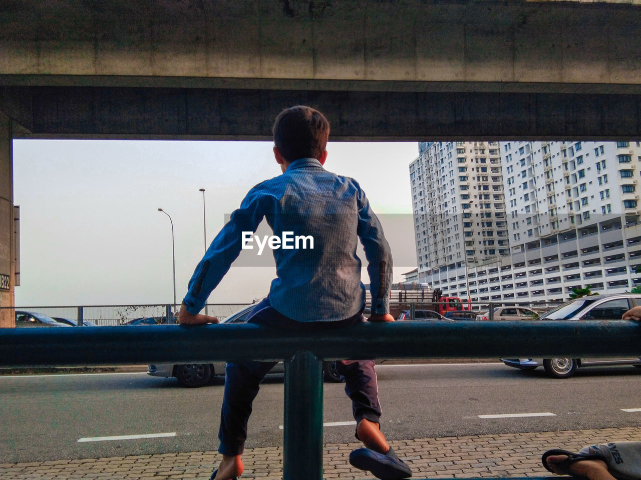 REAR VIEW OF MAN ON BRIDGE IN CITY