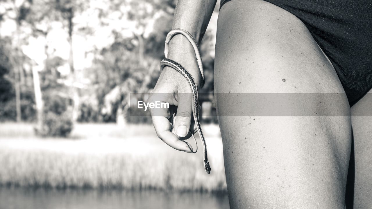 Midsection of woman in swimwear holding snake