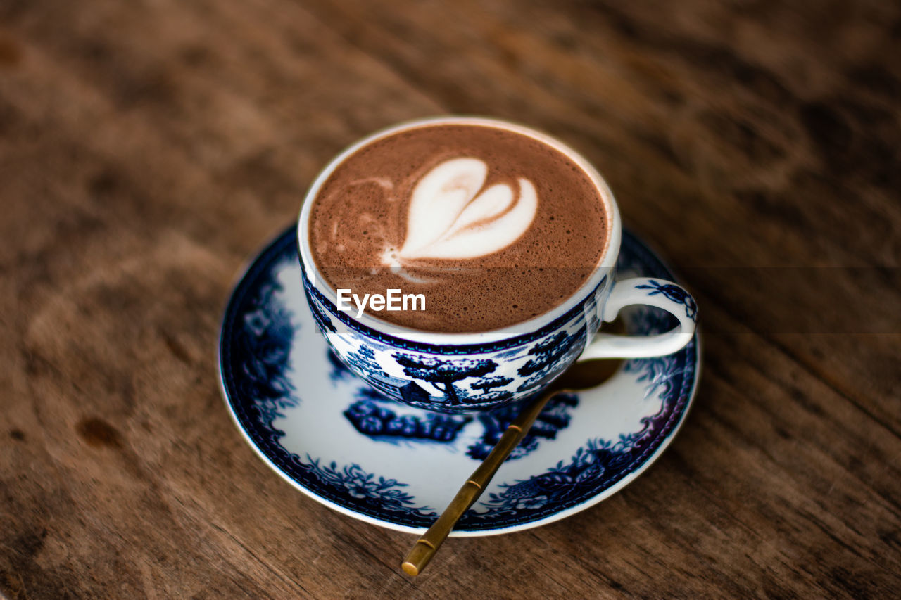 coffee, drink, mug, cup, food and drink, coffee cup, refreshment, saucer, crockery, hot drink, cappuccino, frothy drink, wood, table, froth art, still life, spoon, latte, kitchen utensil, eating utensil, food, no people, flat white, indoors, freshness, coffee milk, high angle view, heart shape, close-up, pattern, cortado, brown, teaspoon, cafe