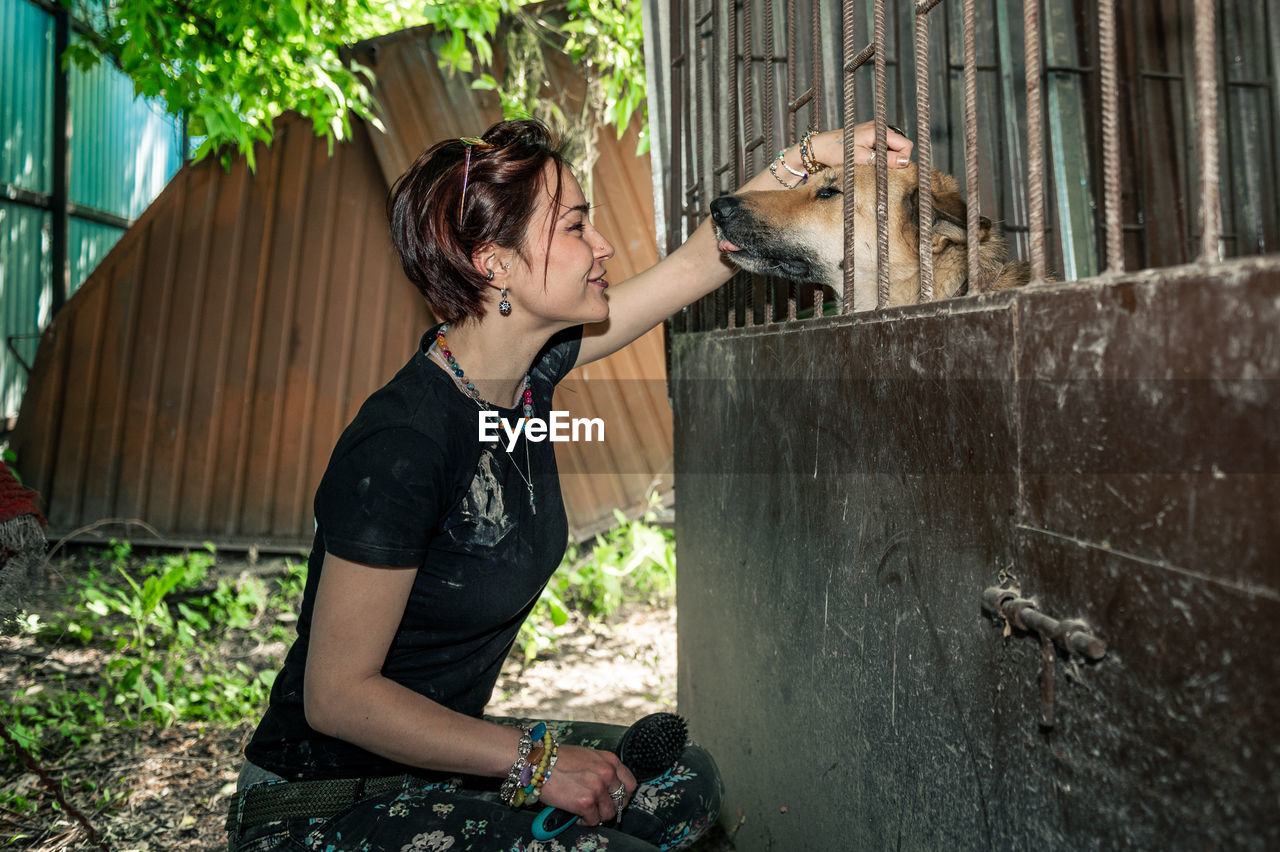 Dog at the shelter.  lonely dogs in cage with cheerful woman volunteer