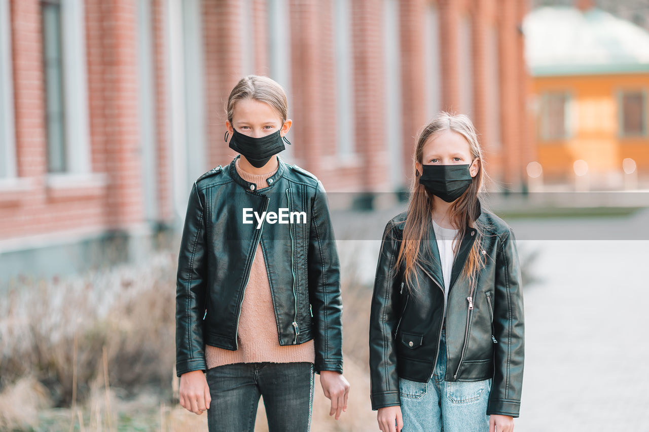 Portrait of girls wearing masks while standing outdoors