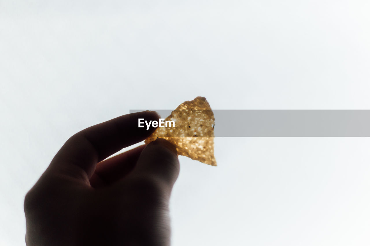 Close-up of hand holding bread against clear sky