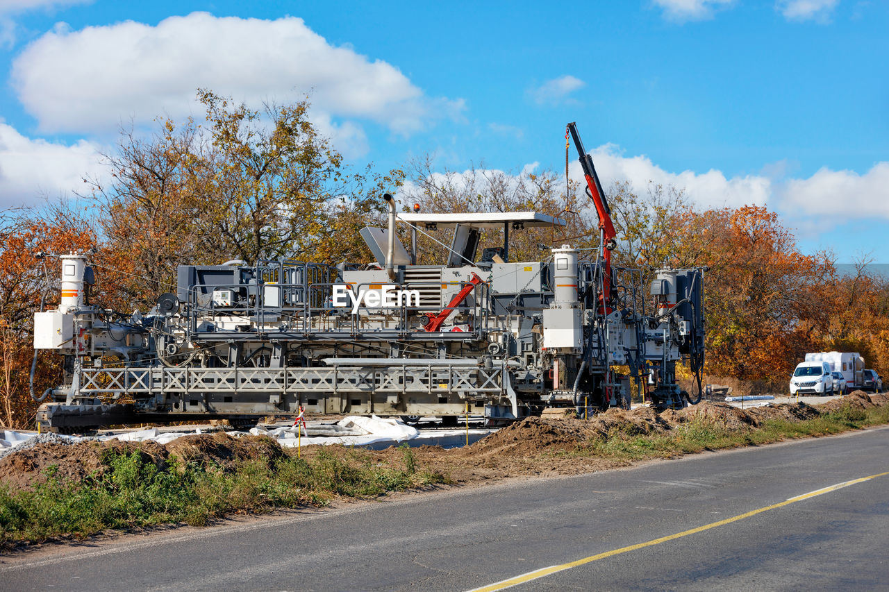 VEHICLES ON ROAD AGAINST PLANTS AND TREES