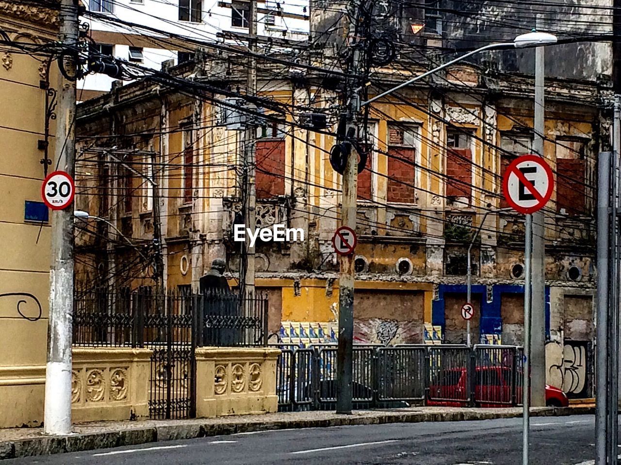 Electricity pylon on sidewalk by building