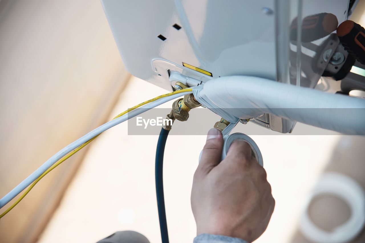 Man is installing wall compressor of air conditioner during hot season