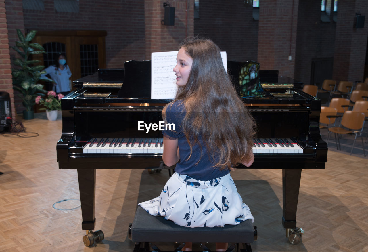 Teenage girl playing the piano in the concert hall, hobby, music