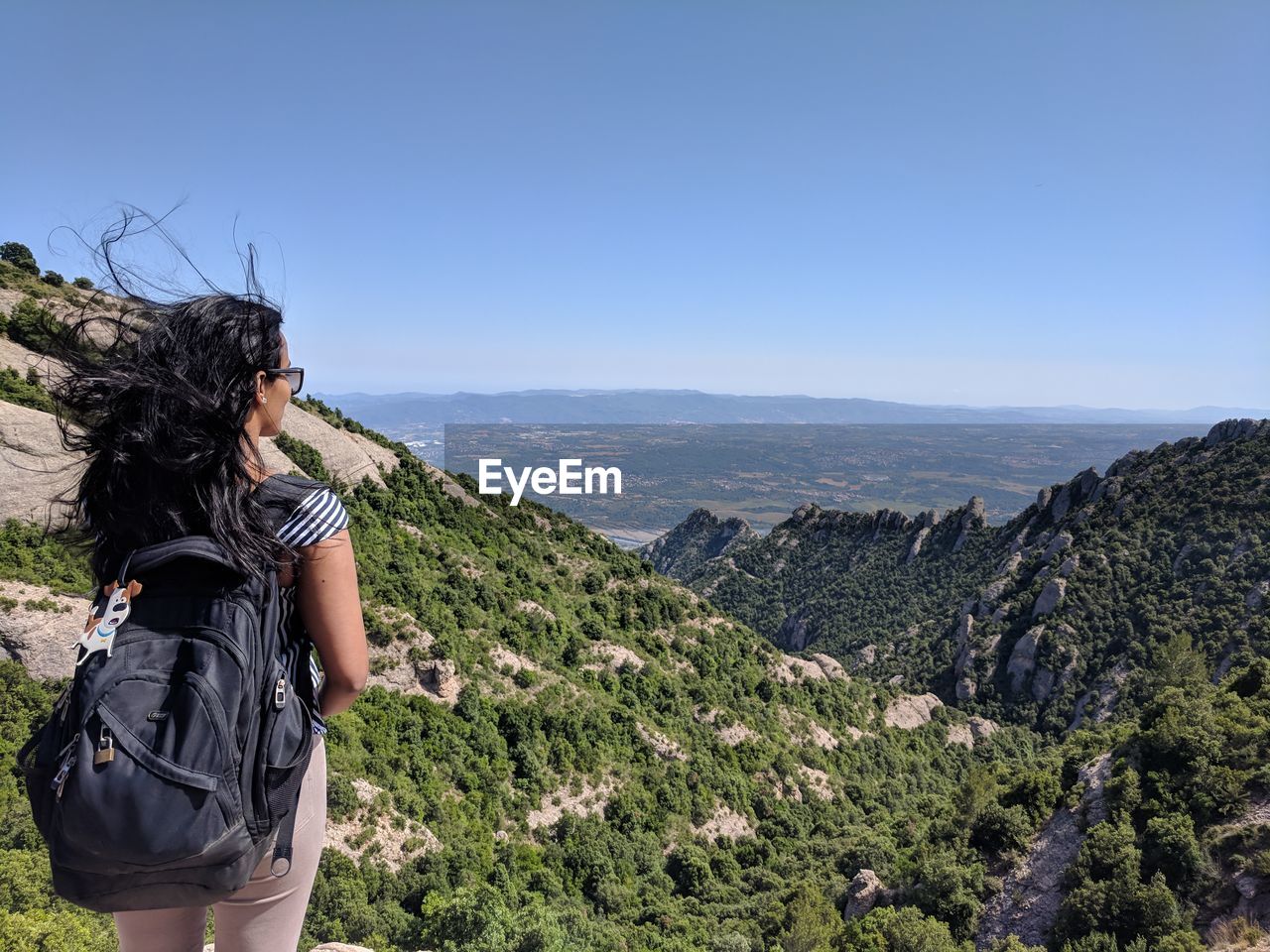 Rear view of woman looking at mountains against clear blue sky