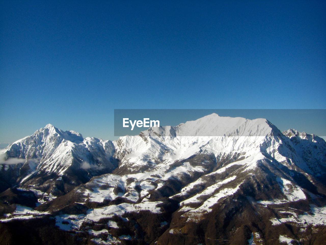 Scenic view of snowcapped mountains against clear blue sky