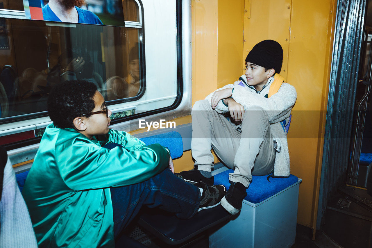 Male friends talking with each other while sitting in tram
