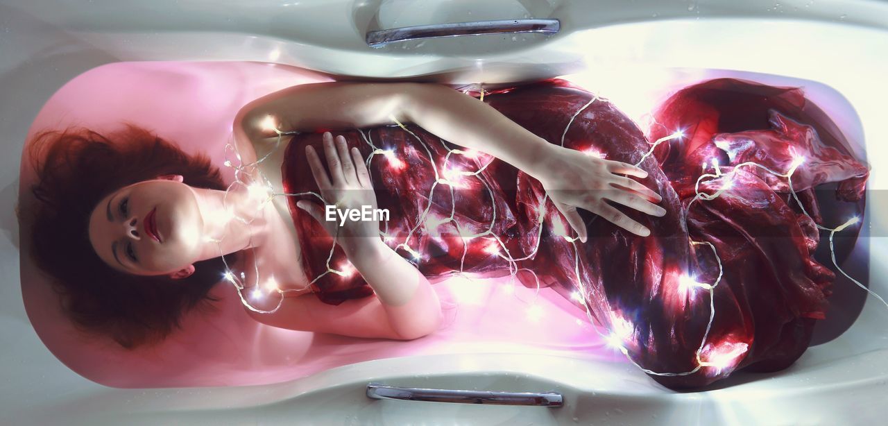 Directly above view of young woman wearing led strip lights in bathtub