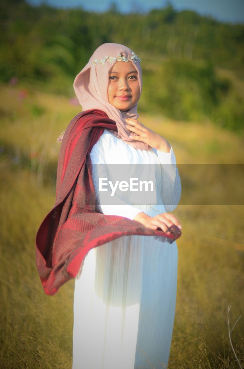 Portrait of bride wearing hijab while standing on field