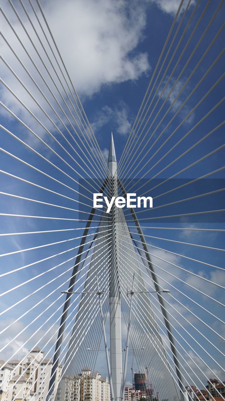 Low angle view of suspension bridge against cloudy sky