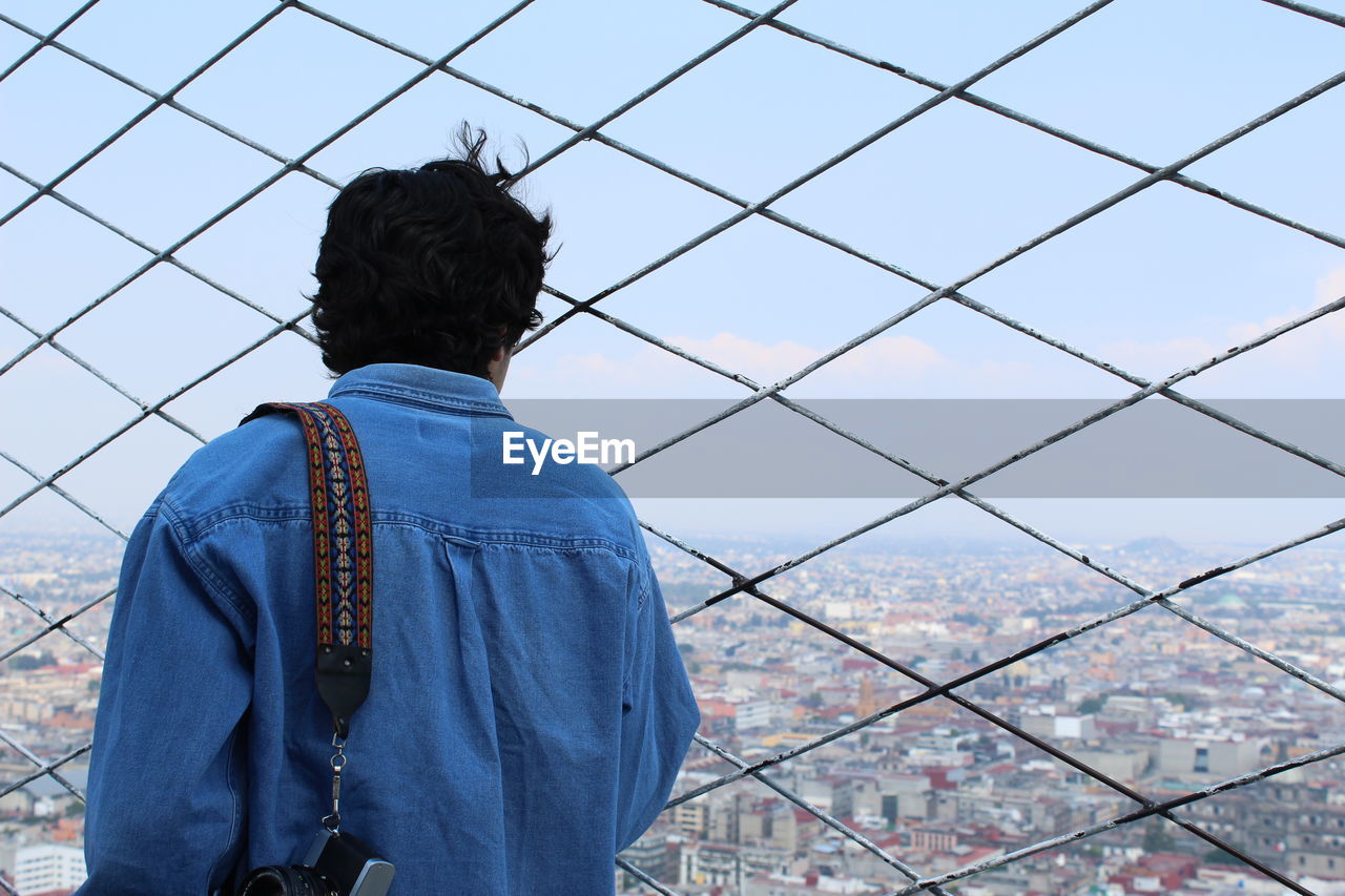 Rear view of man looking at cityscape while standing at observation point