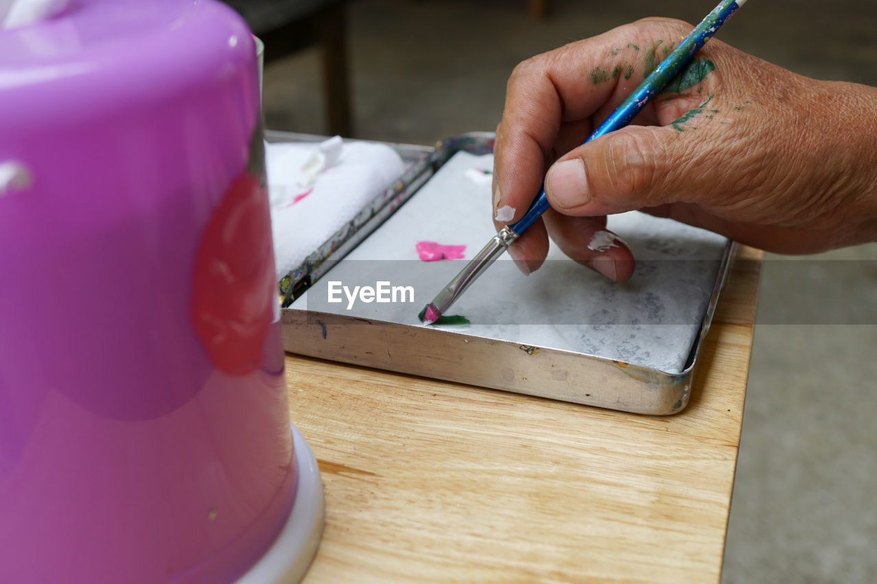 Cropped hand of man painting on table