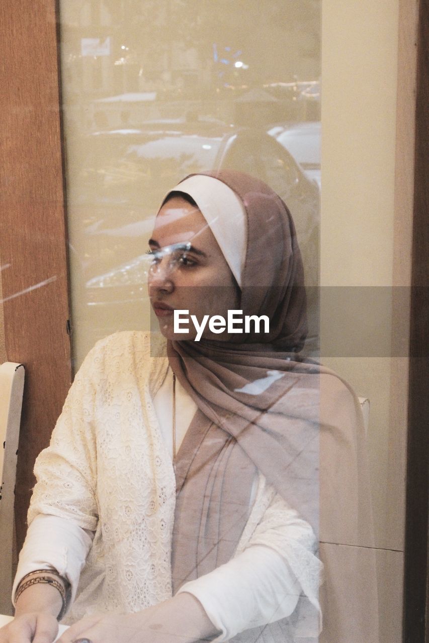 Woman in headscarf seen through glass window