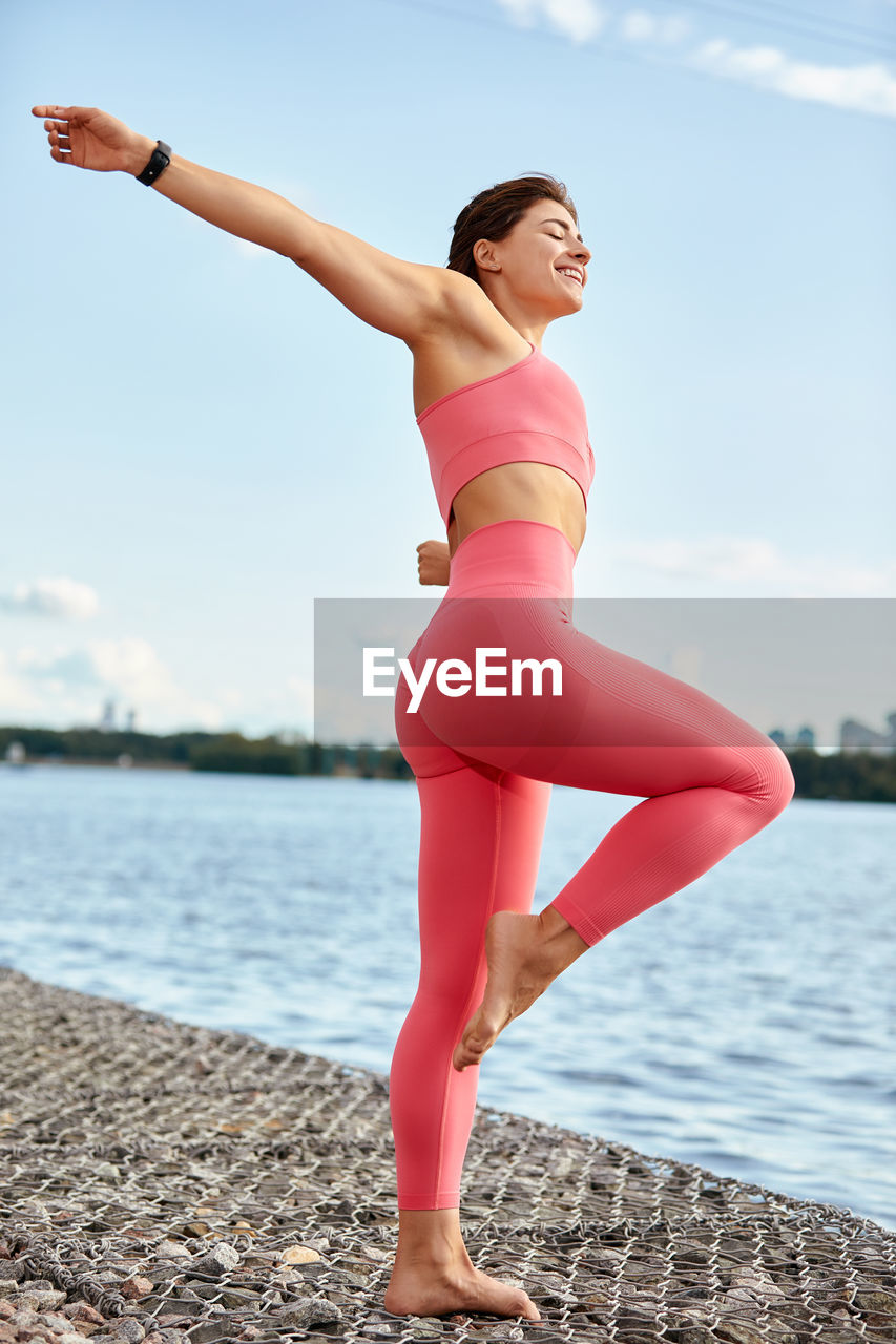 full length of young woman doing yoga on beach