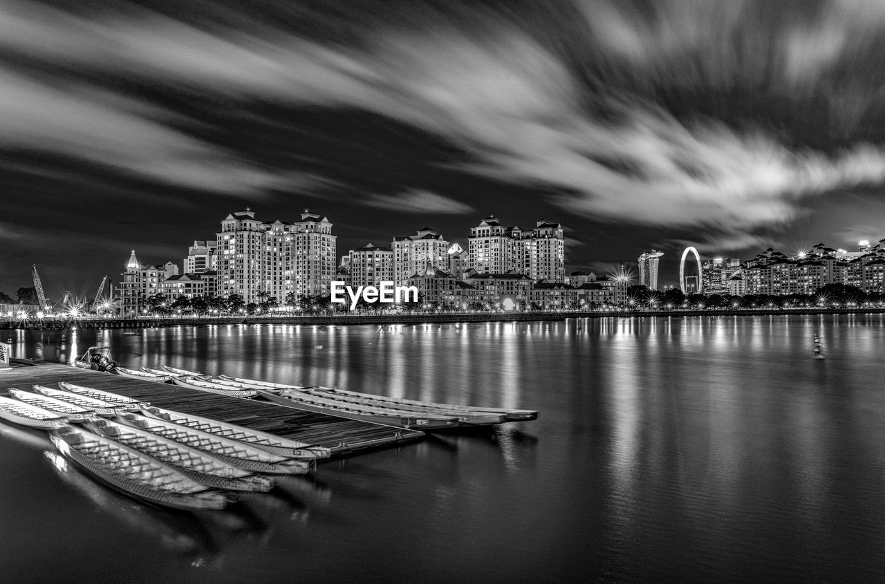 Panoramic view of illuminated buildings by sea against sky at night