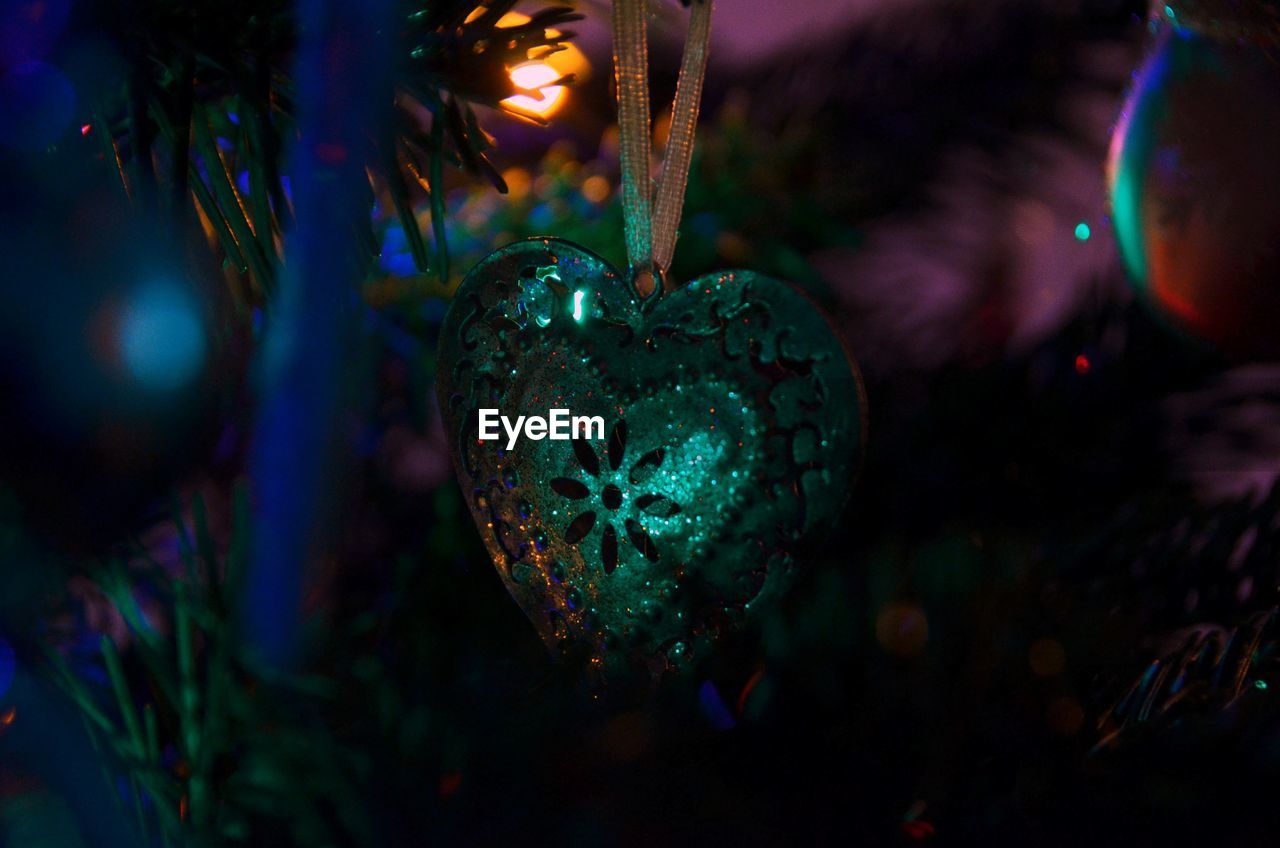 Close-up of heart shape hanging on christmas tree at night