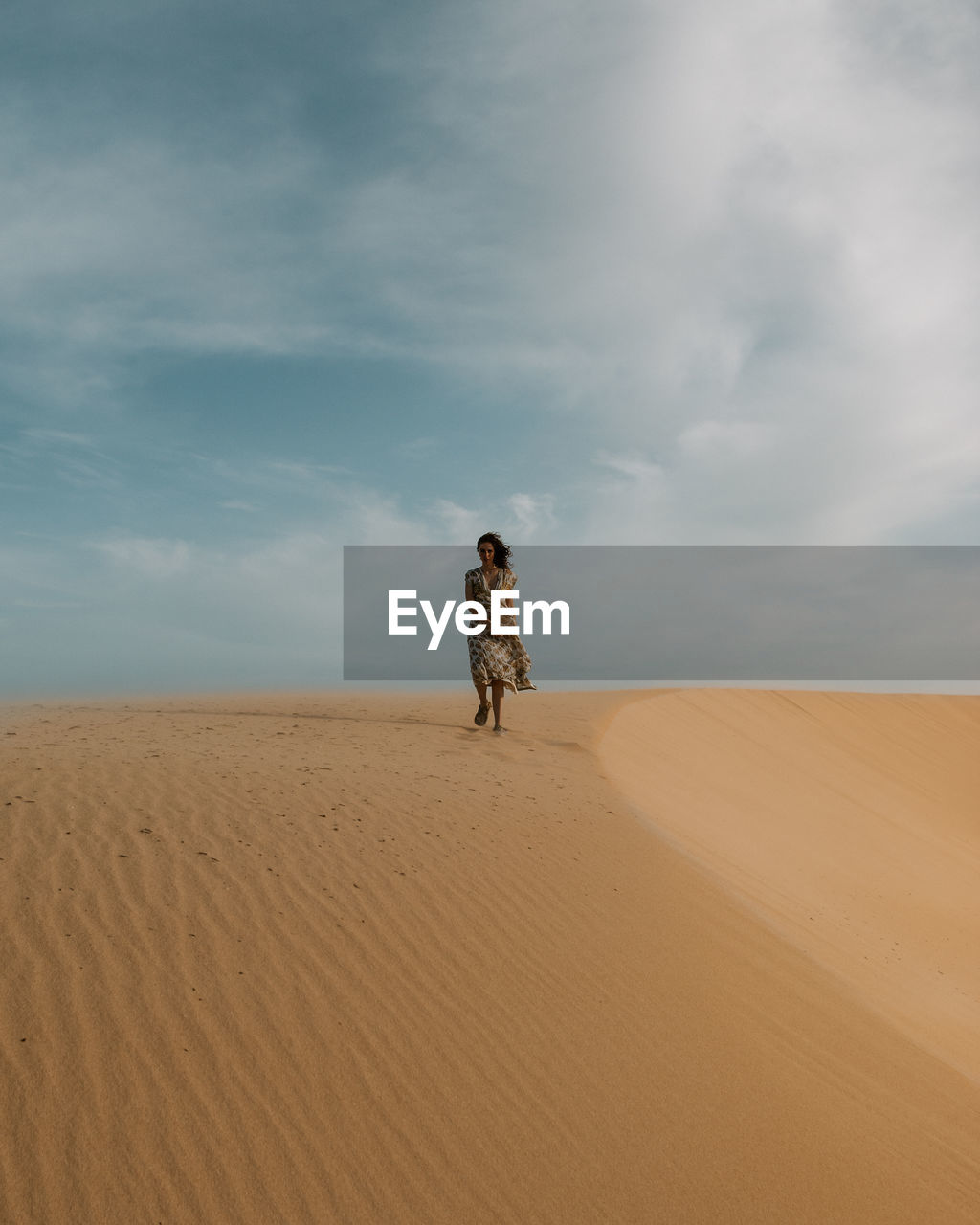 Woman standing on a sand dune in desert against sky