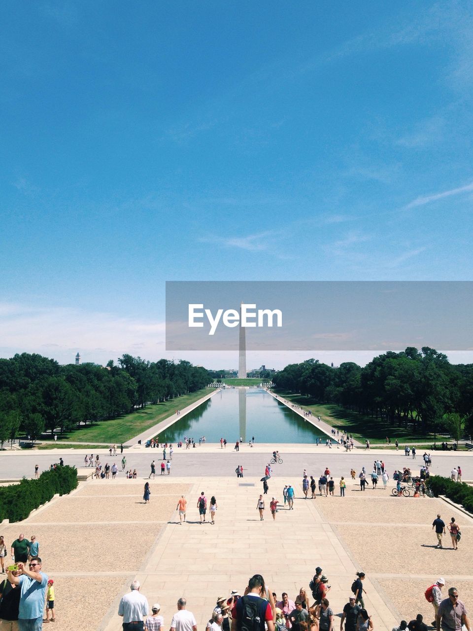 People watching washington monument against blue sky