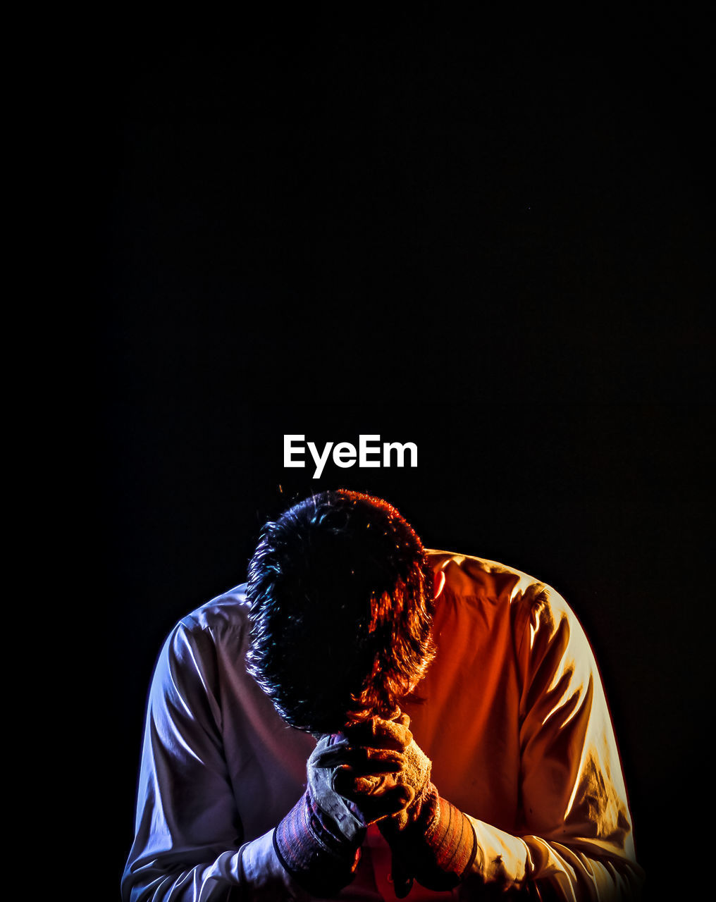 Depressed man standing against black background