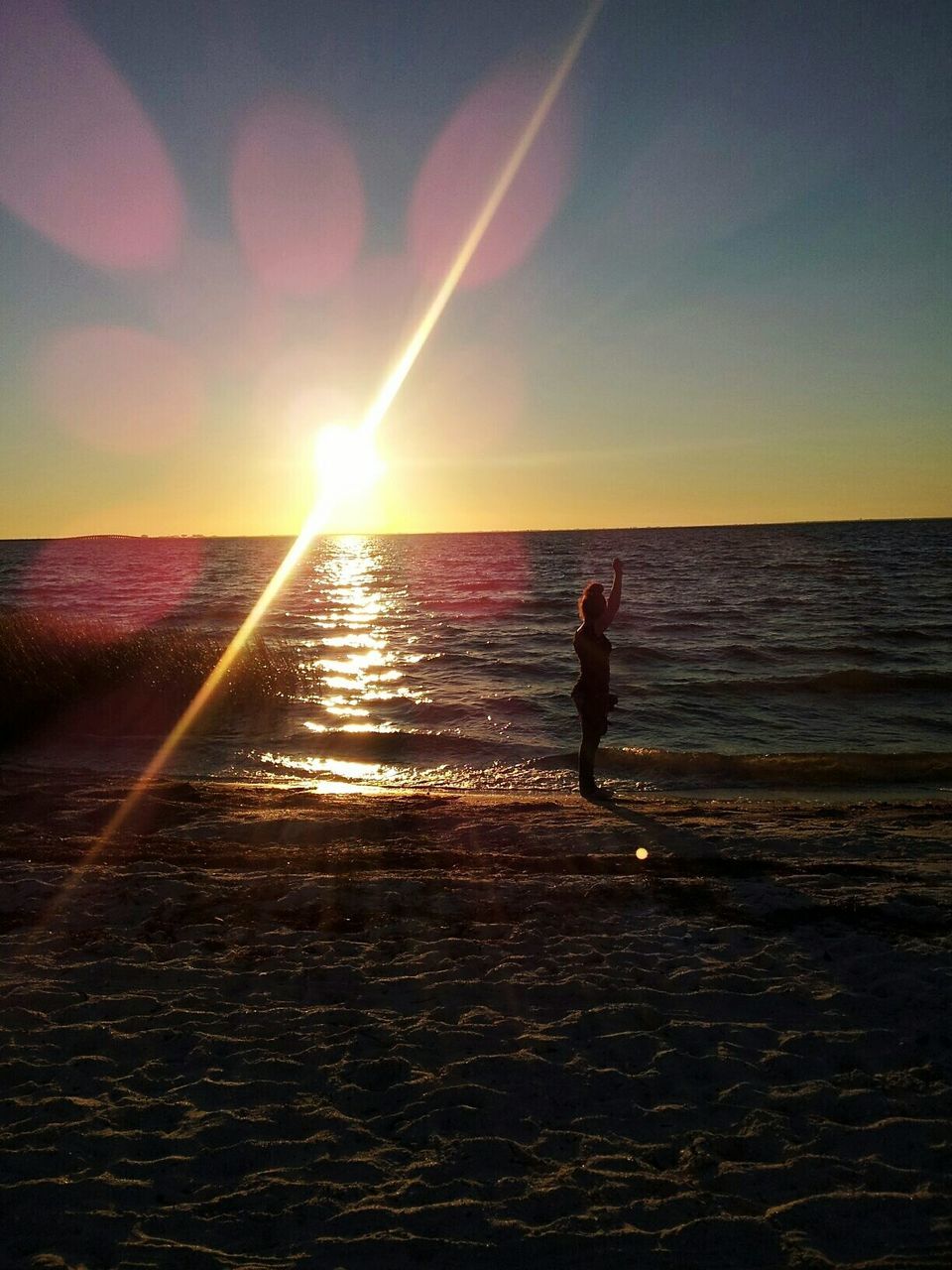 SILHOUETTE MAN STANDING ON BEACH AGAINST SKY AT SUNSET