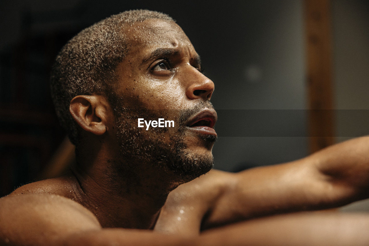 Determined male athlete looking away while working out in gym