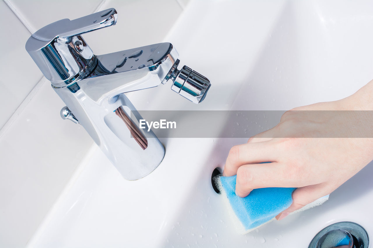 Close-up of person cleaning sink in bathroom