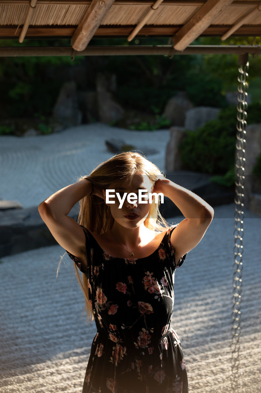 Portrait of young woman standing against trees