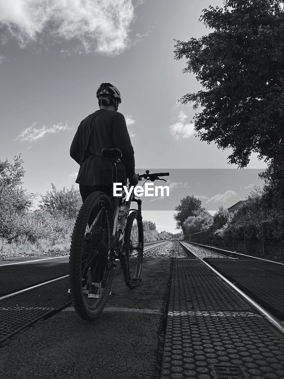 Cyclist holding a bicycle looking up a railway line