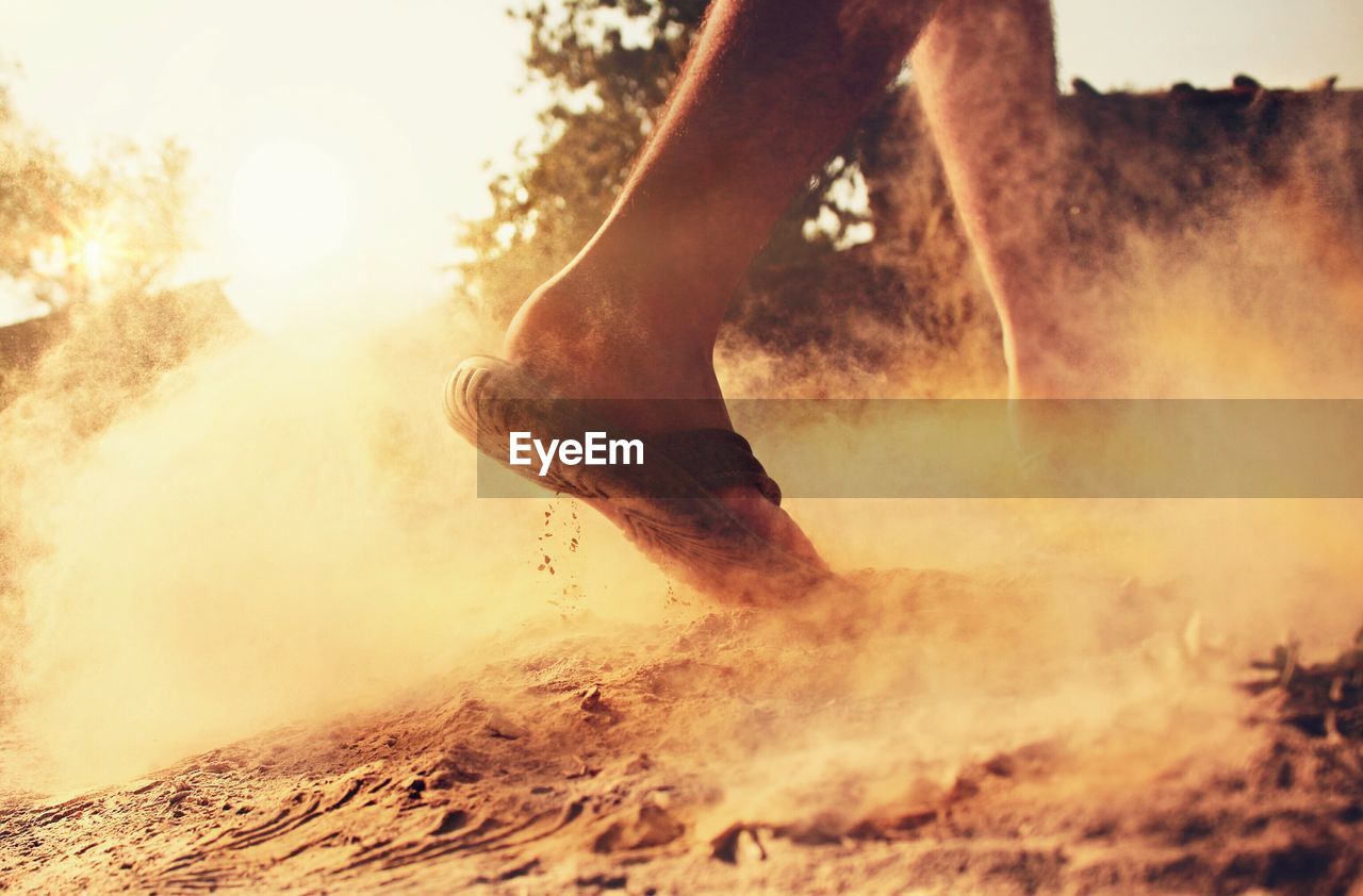 Low section of man walking on dirt road