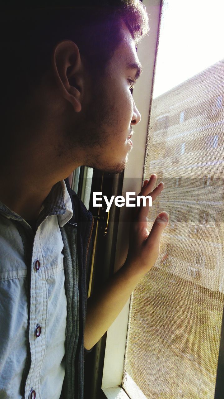 Close-up of man looking through window