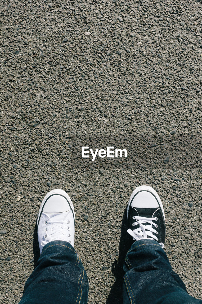 Low section of man wearing different shoes on street