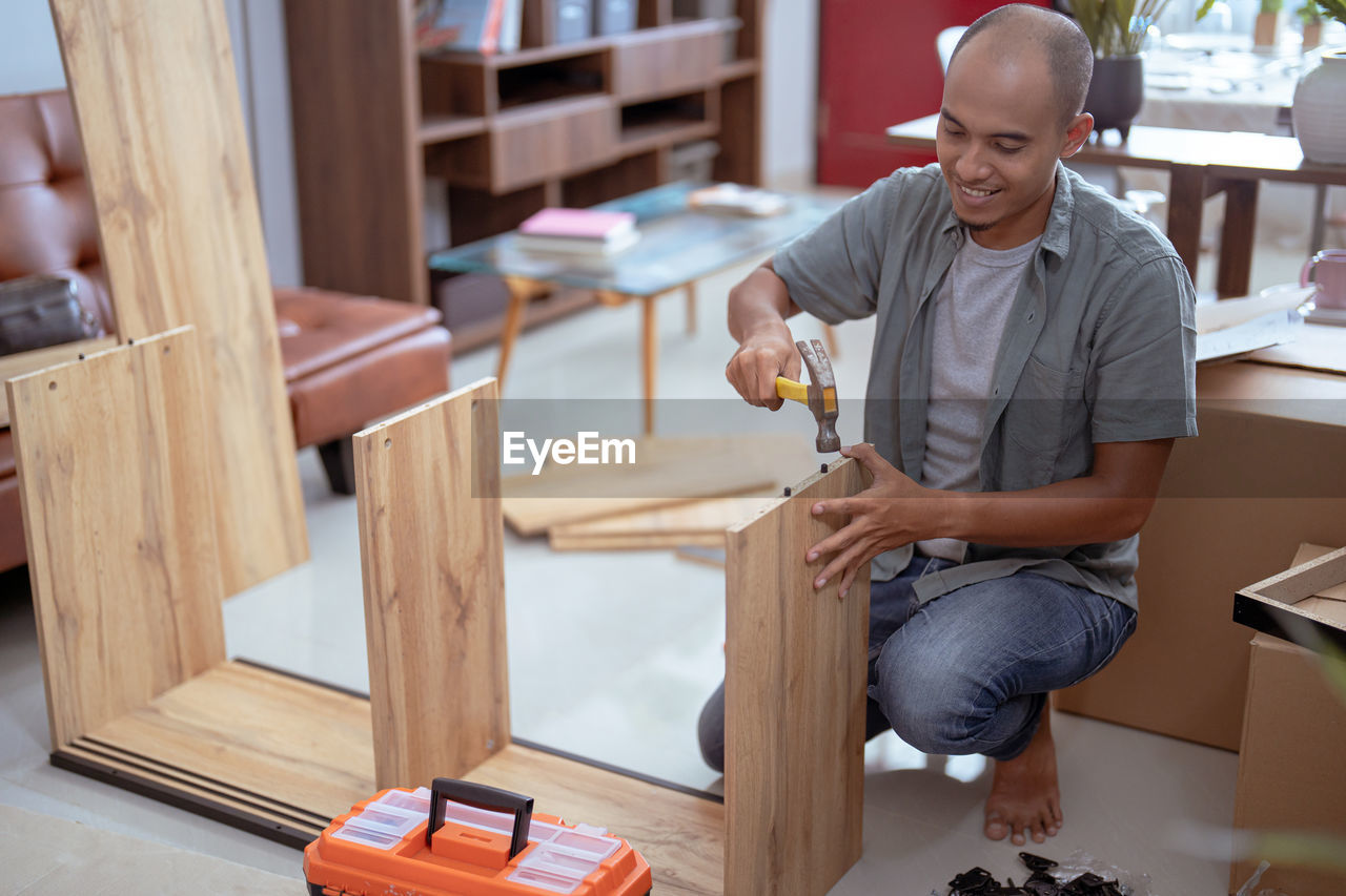 portrait of young man playing with toy blocks while sitting at home