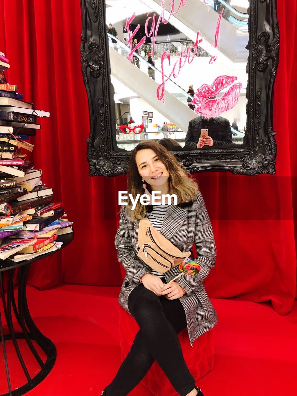 Portrait of young woman sitting against mirror