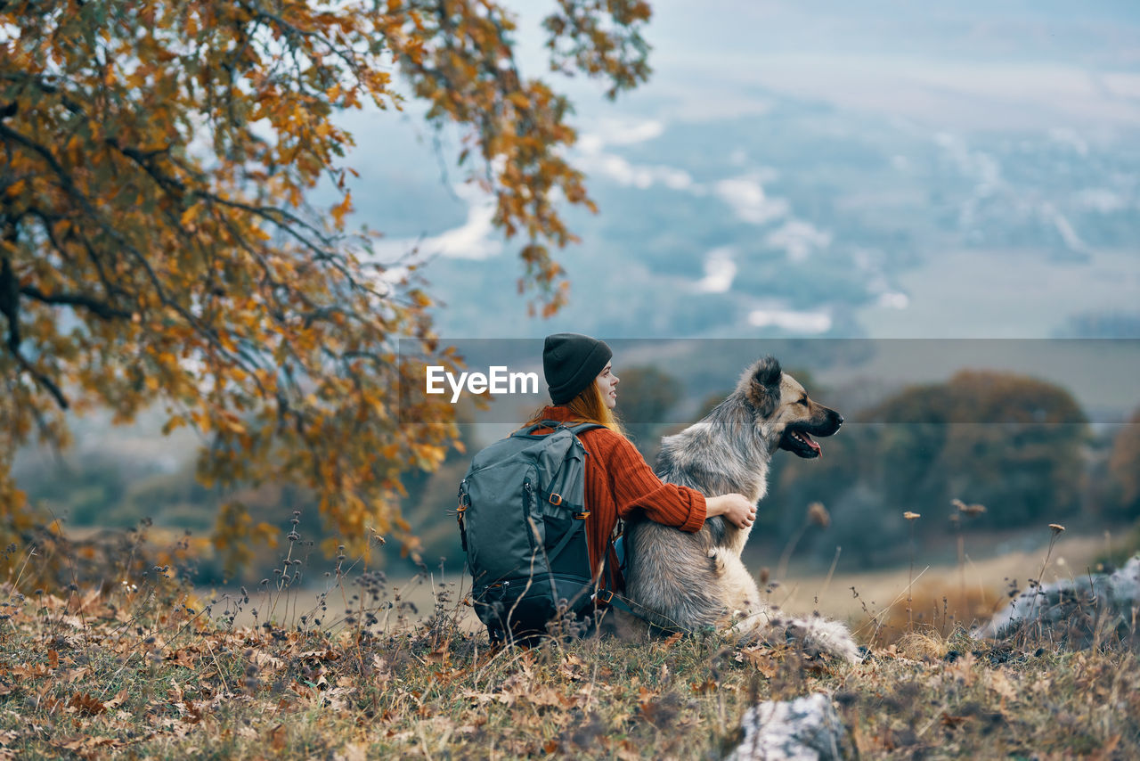 REAR VIEW OF WOMAN WITH DOG IN BACKGROUND