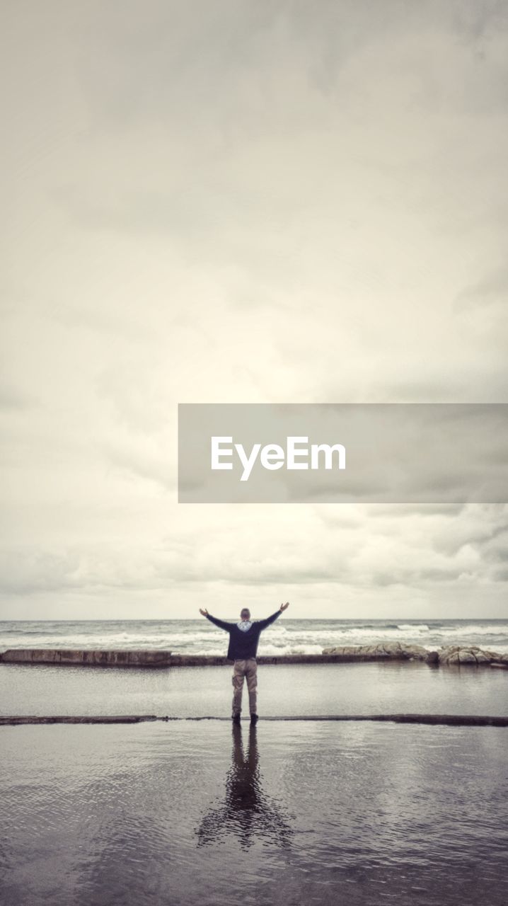 Rear view of man standing on sea against sky