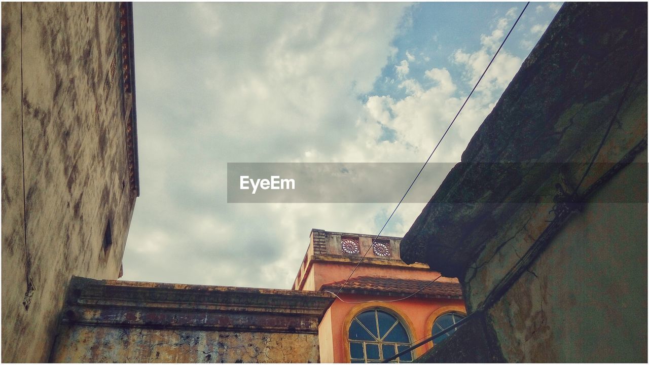 Low angle view of old buildings against cloudy sky