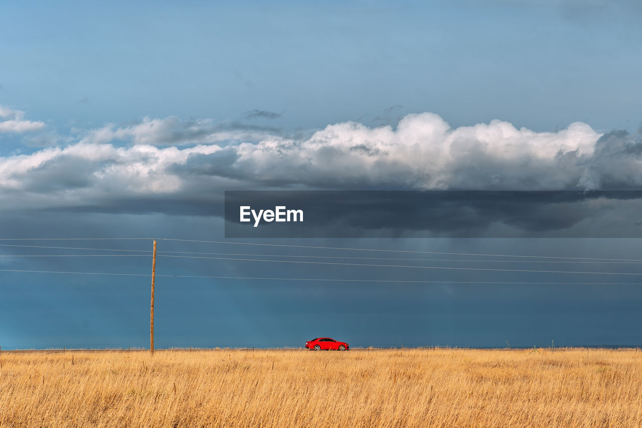 Scenic view of field with car in background against sky