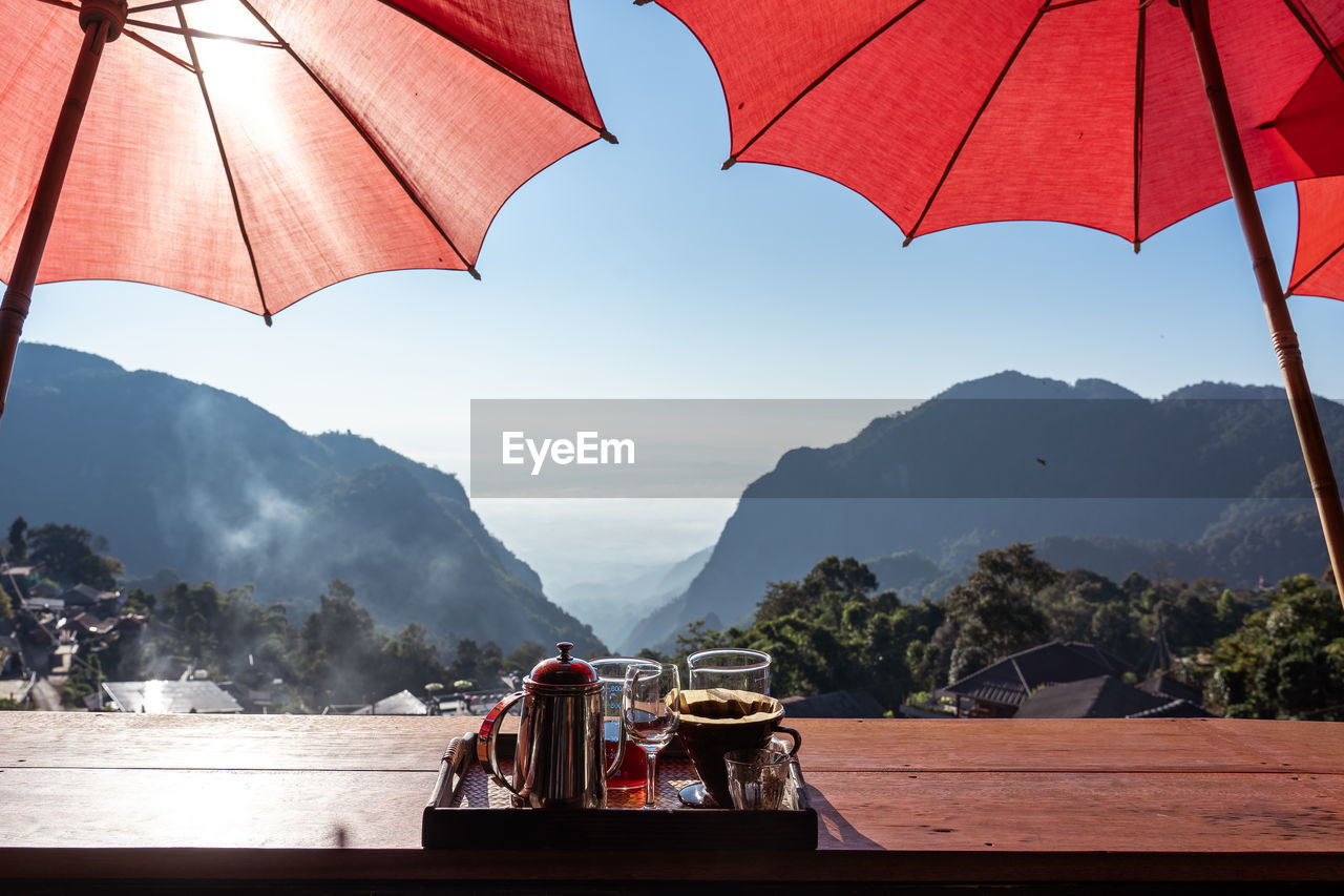 UMBRELLAS ON TABLE AGAINST MOUNTAINS AGAINST SKY