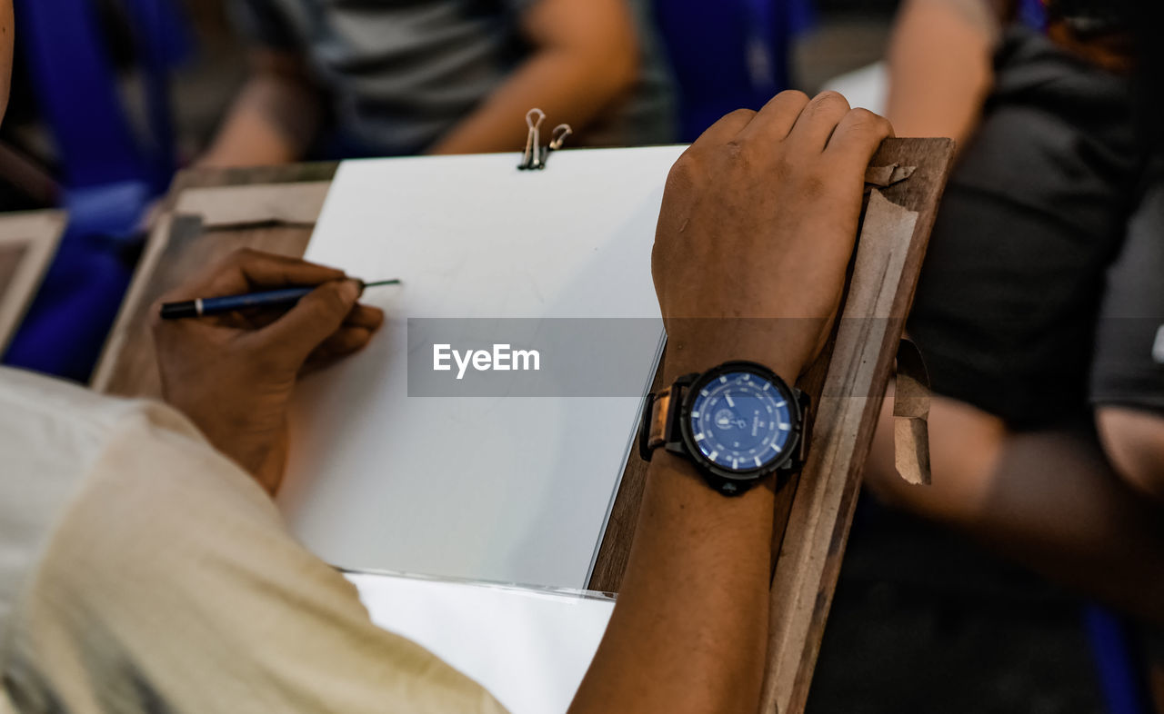 Cropped image of man sketching on paper