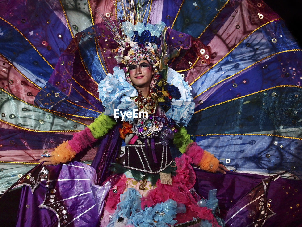 PORTRAIT OF WOMAN HOLDING MULTI COLORED TRADITIONAL CLOTHING