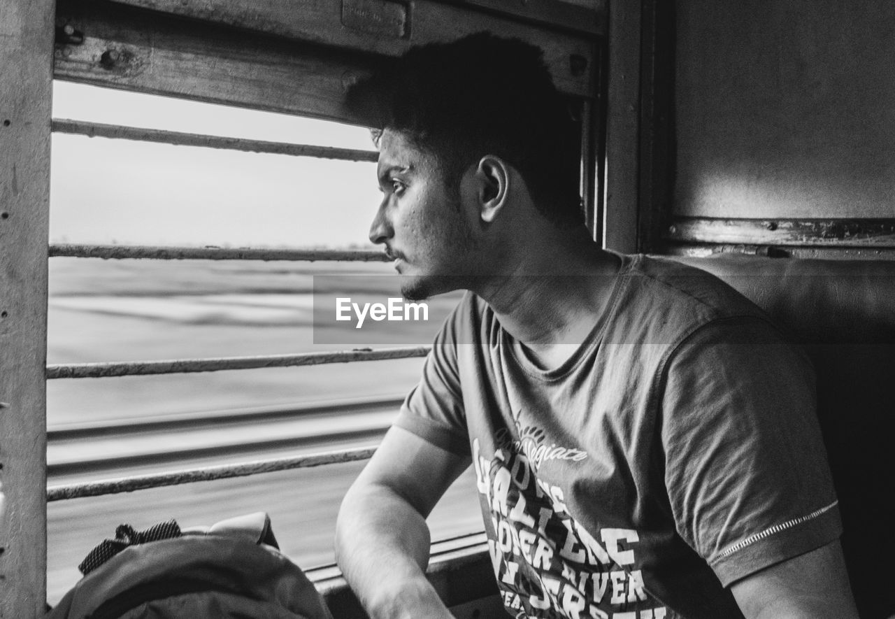 Close-up of young man looking through train window