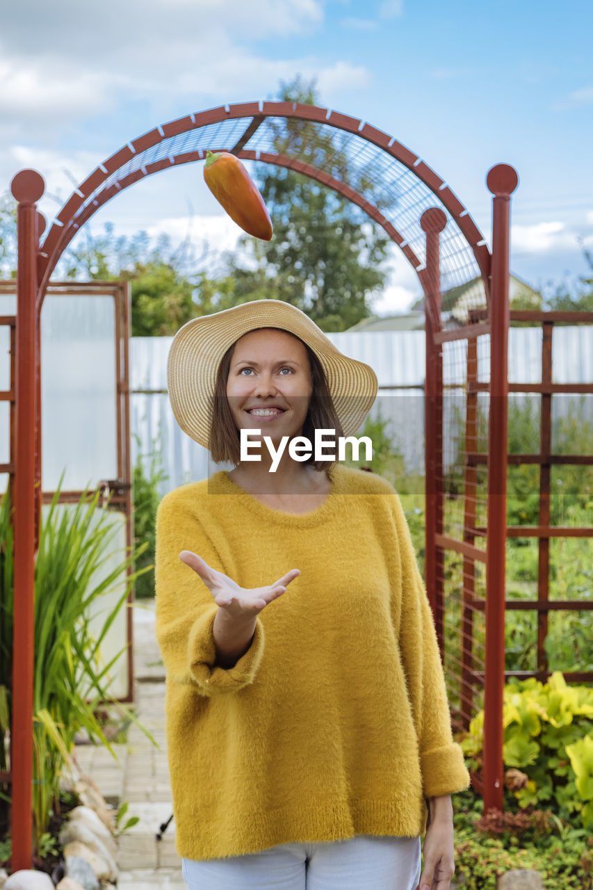 Woman playing with bell pepper while standing at greenhouse