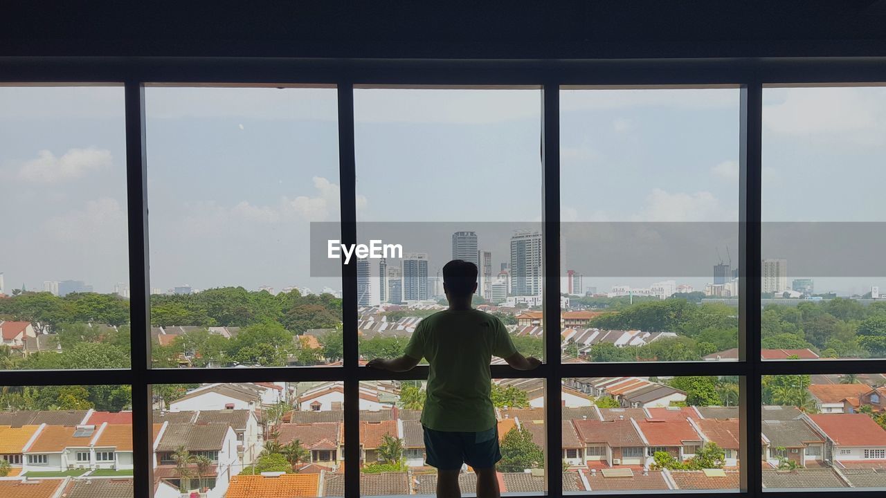 Rear view of man looking through window