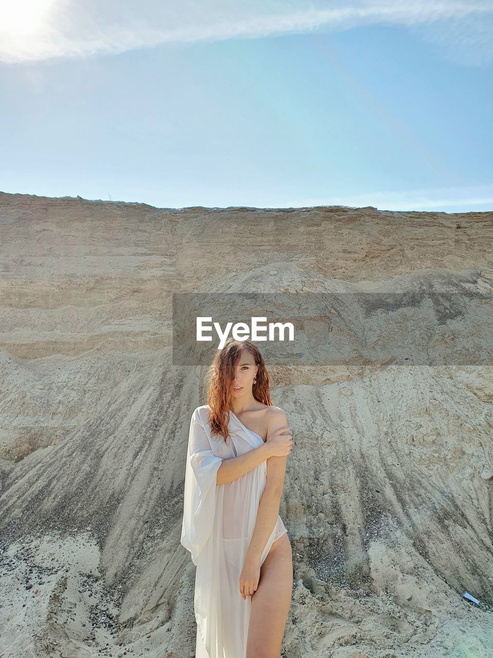 Beautiful young woman standing against sky