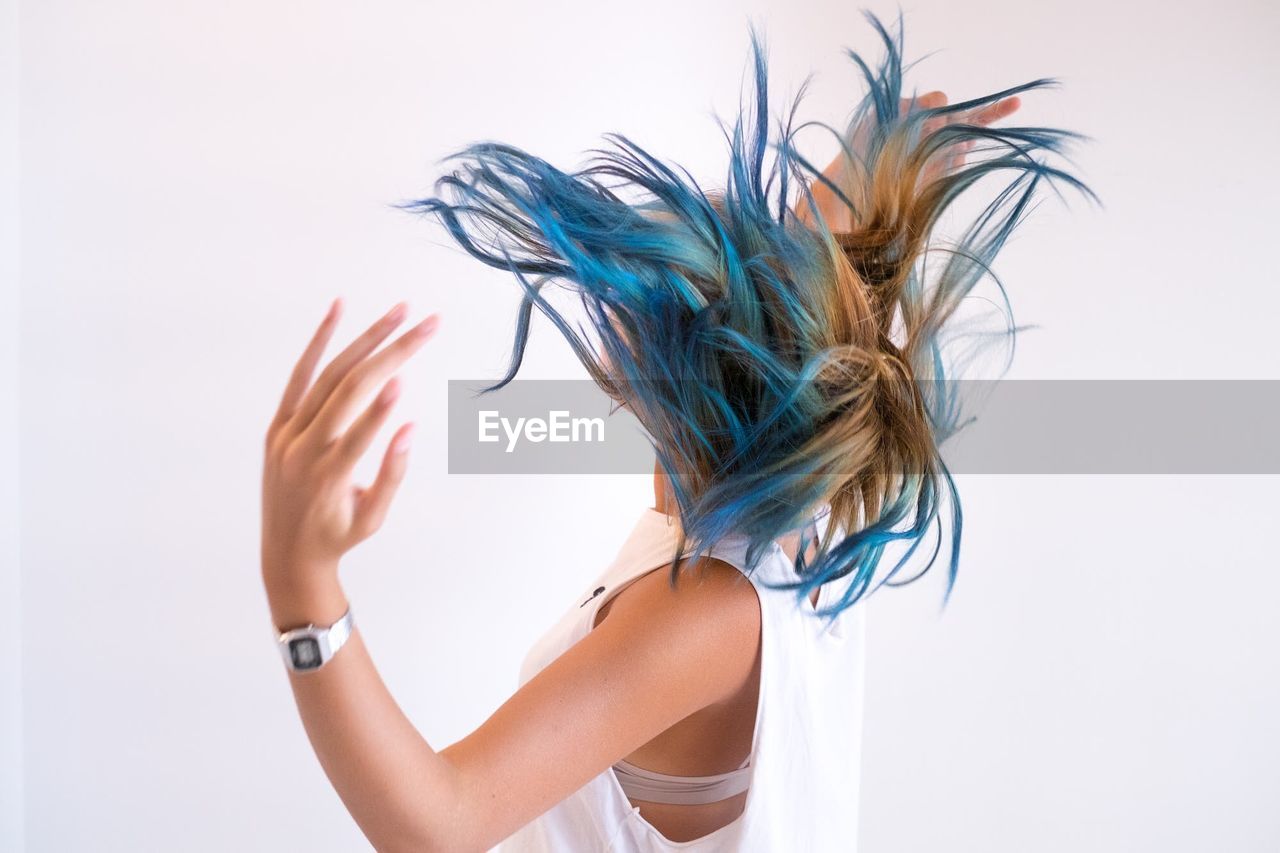 Side view of woman tossing hair against white background