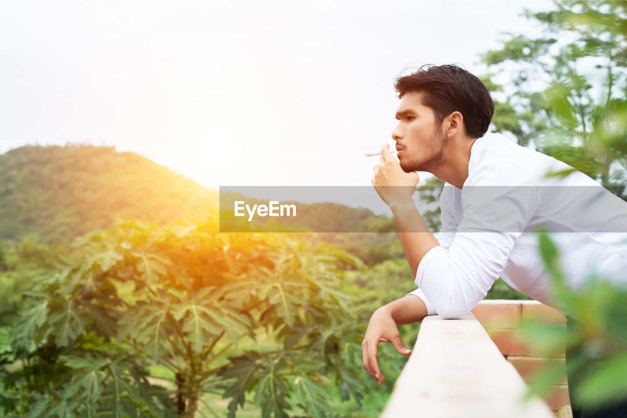 Man smoking cigarette against sky