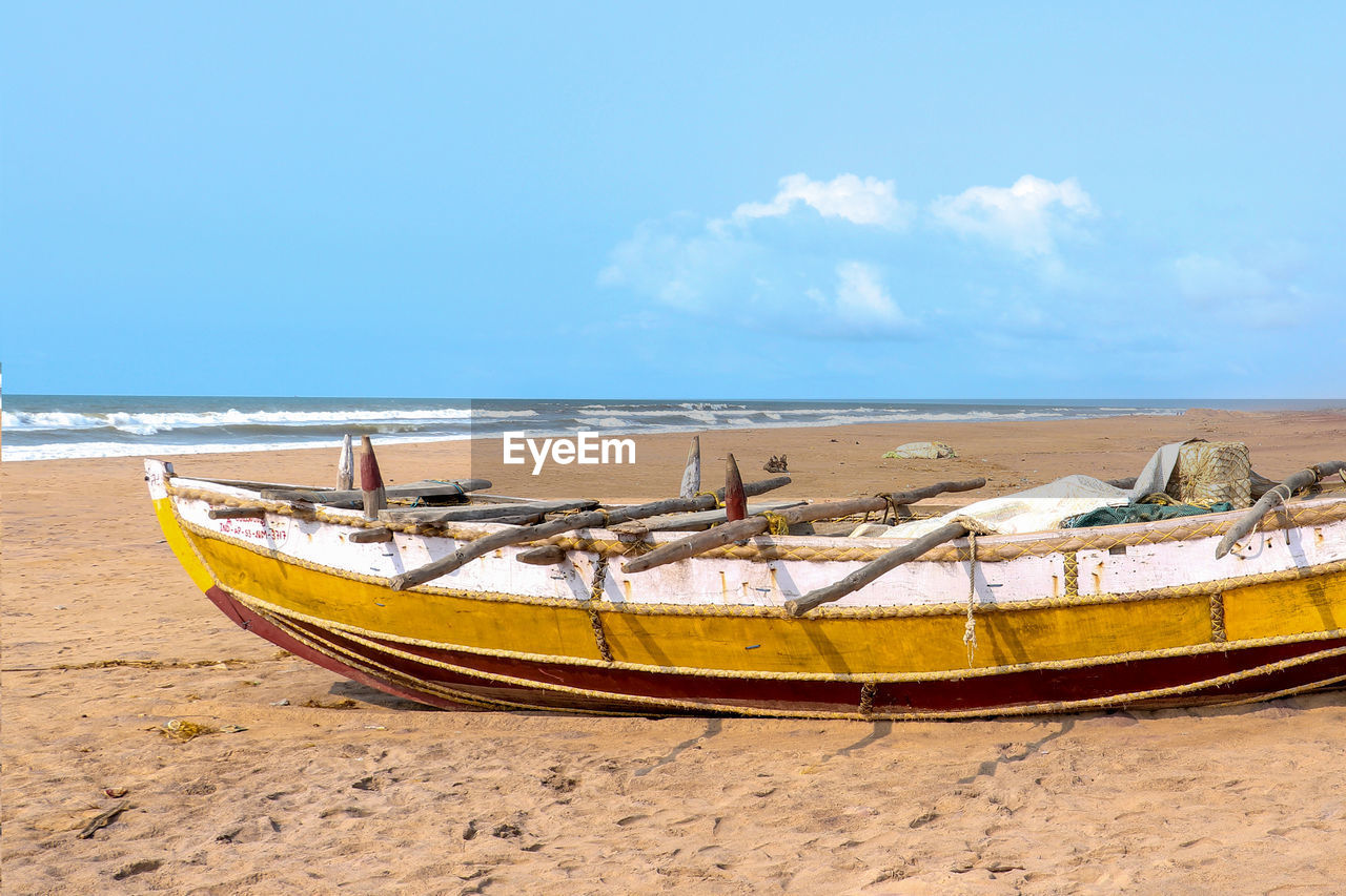 Boat moored on beach against sky